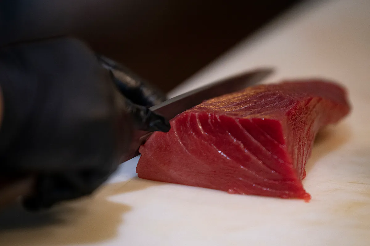 Close-up of a knife slicing a piece of raw tuna at Shiki Sushi，a Japanese Restaurant in Santa Rosa